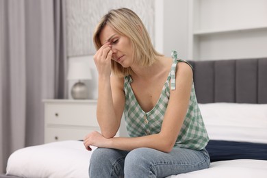 Photo of Overwhelmed woman sitting on bed at home