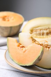 Photo of Tasty colorful ripe melons on white wooden table, closeup