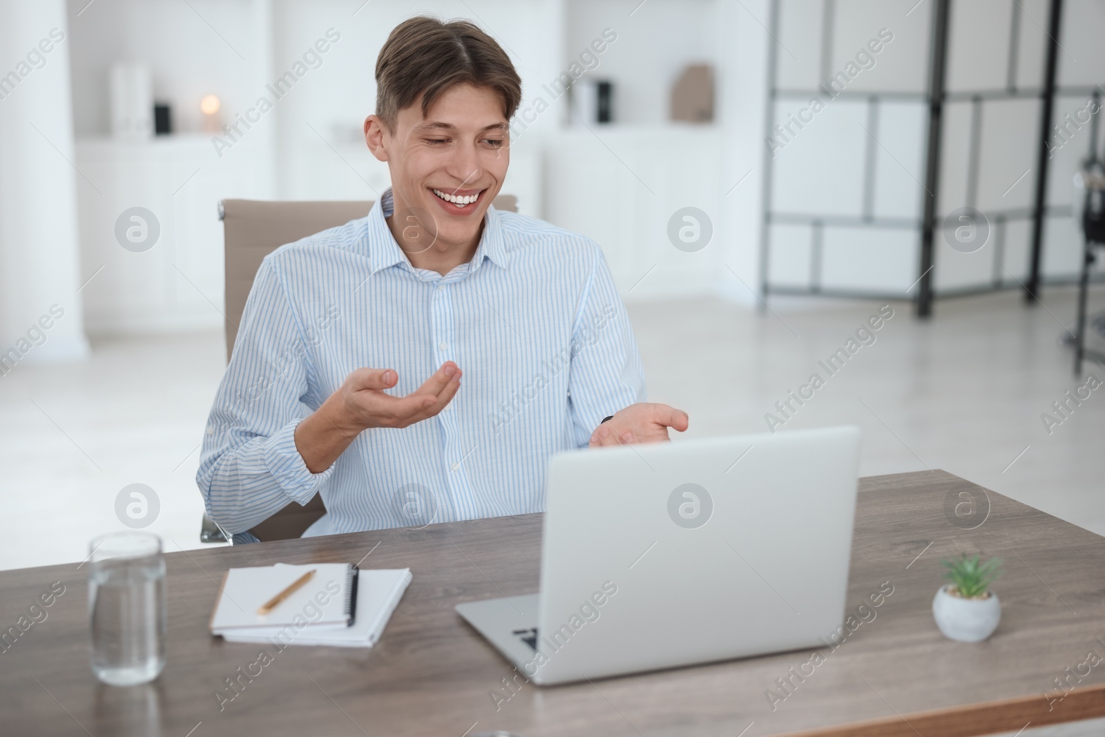 Photo of Man using video chat during webinar at wooden table in office