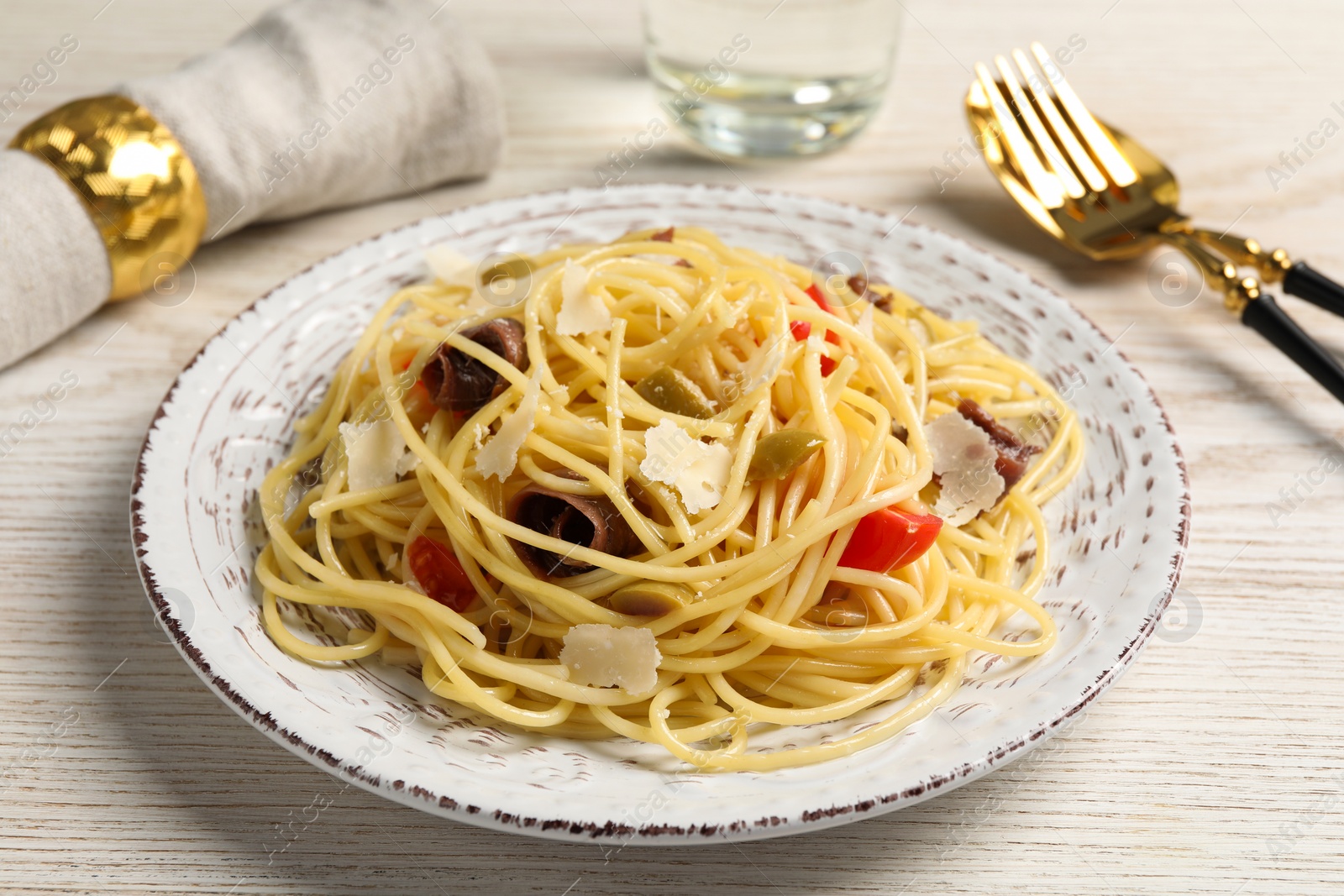 Photo of Delicious pasta with anchovies, tomatoes and parmesan cheese served on white wooden table, closeup