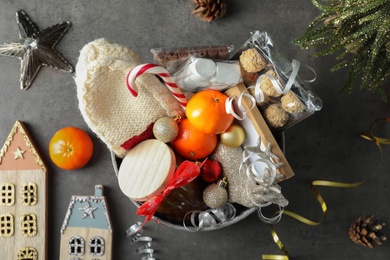 Basket with gift set and Christmas decor on grey table, flat lay