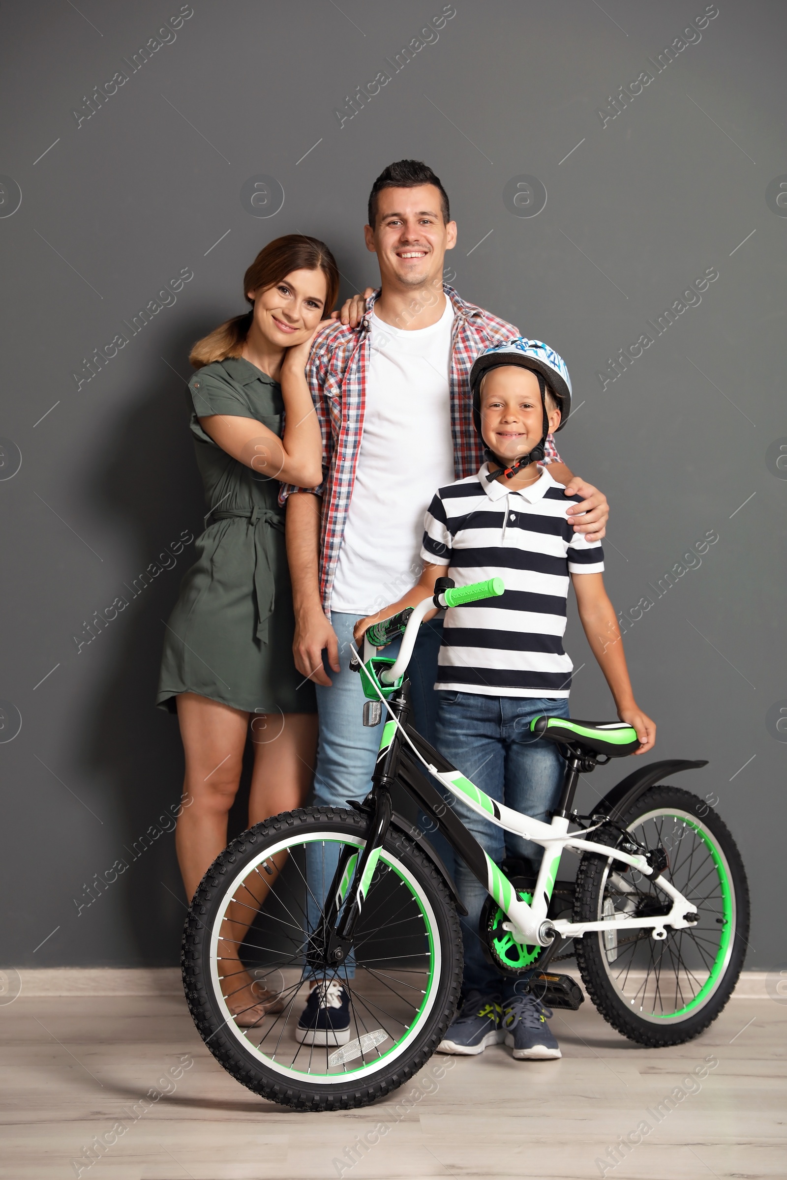 Photo of Portrait of parents and their son with bicycle near color wall