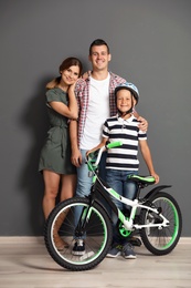 Photo of Portrait of parents and their son with bicycle near color wall
