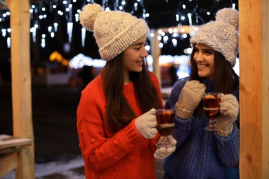 Friends with glass cups of mulled wine at winter fair