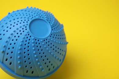 Photo of Laundry dryer ball on yellow background, closeup. Space for text