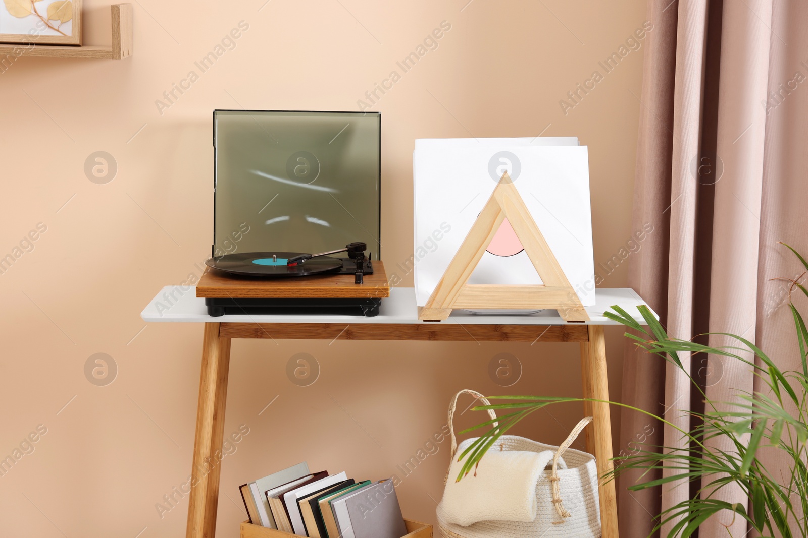 Photo of Stylish turntable with vinyl record on console table in cozy room