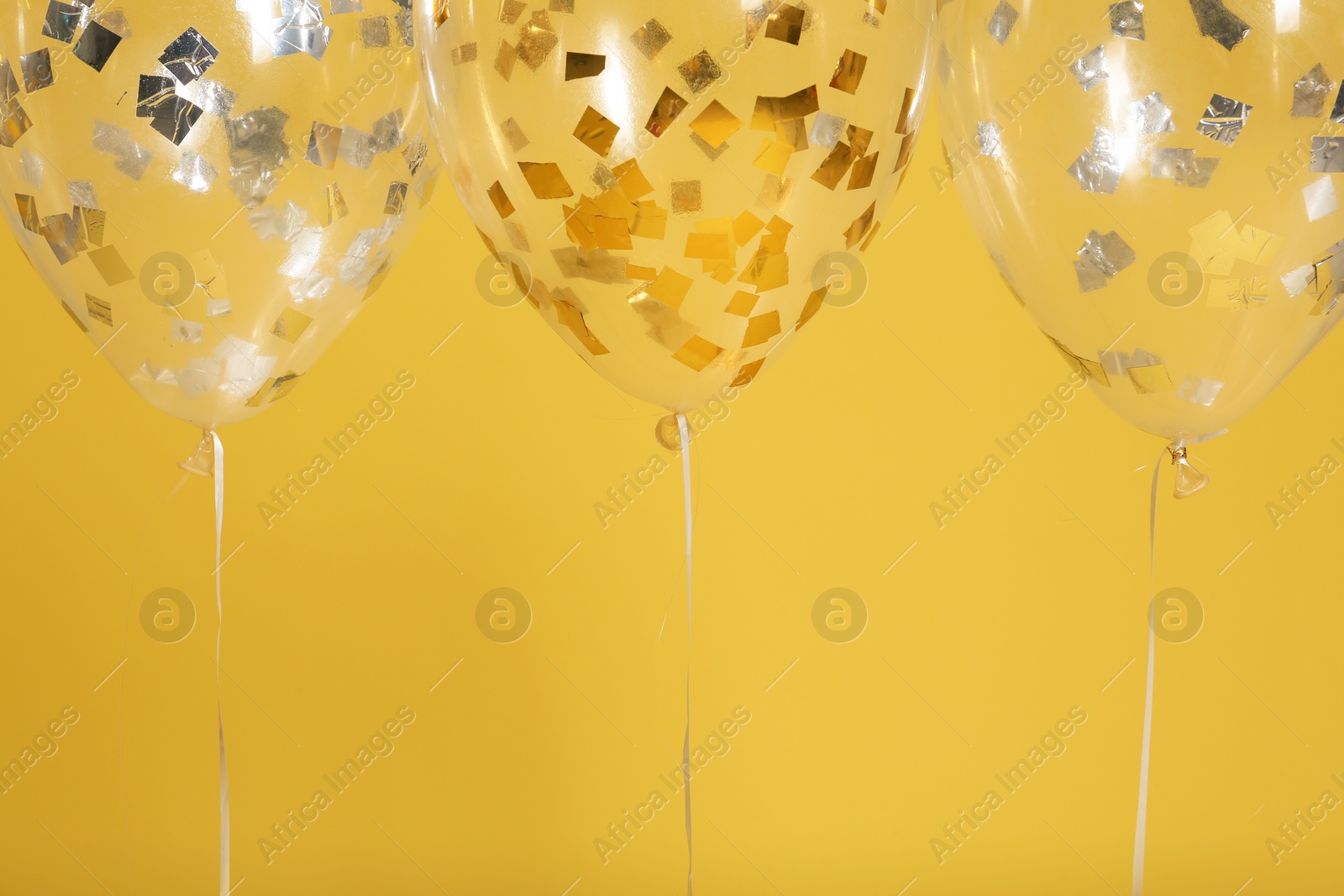 Photo of Bright balloons with ribbons on color background. Space for text