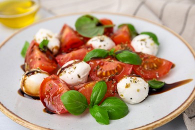 Photo of Tasty salad Caprese with mozarella balls, tomatoes, basil and sauce on table, closeup