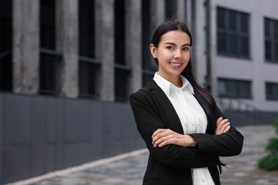 Photo of Portrait of smiling woman with crossed arms outdoors, space for text. Lawyer, businesswoman, accountant or manager