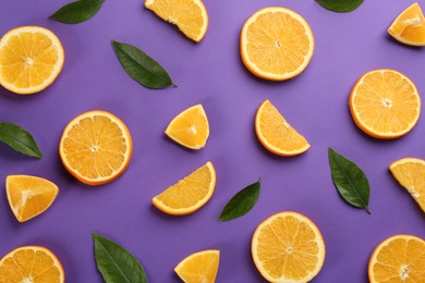 Slices of delicious oranges on purple background, flat lay