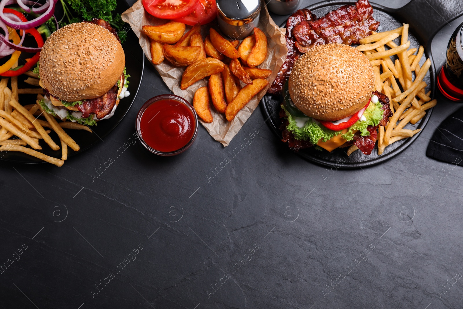 Photo of Flat lay composition with fresh bacon burgers and fries on grey table. Space for text