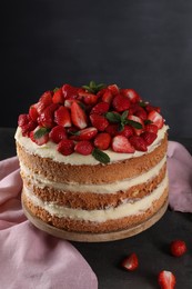 Tasty cake with fresh strawberries and mint on table against dark gray background