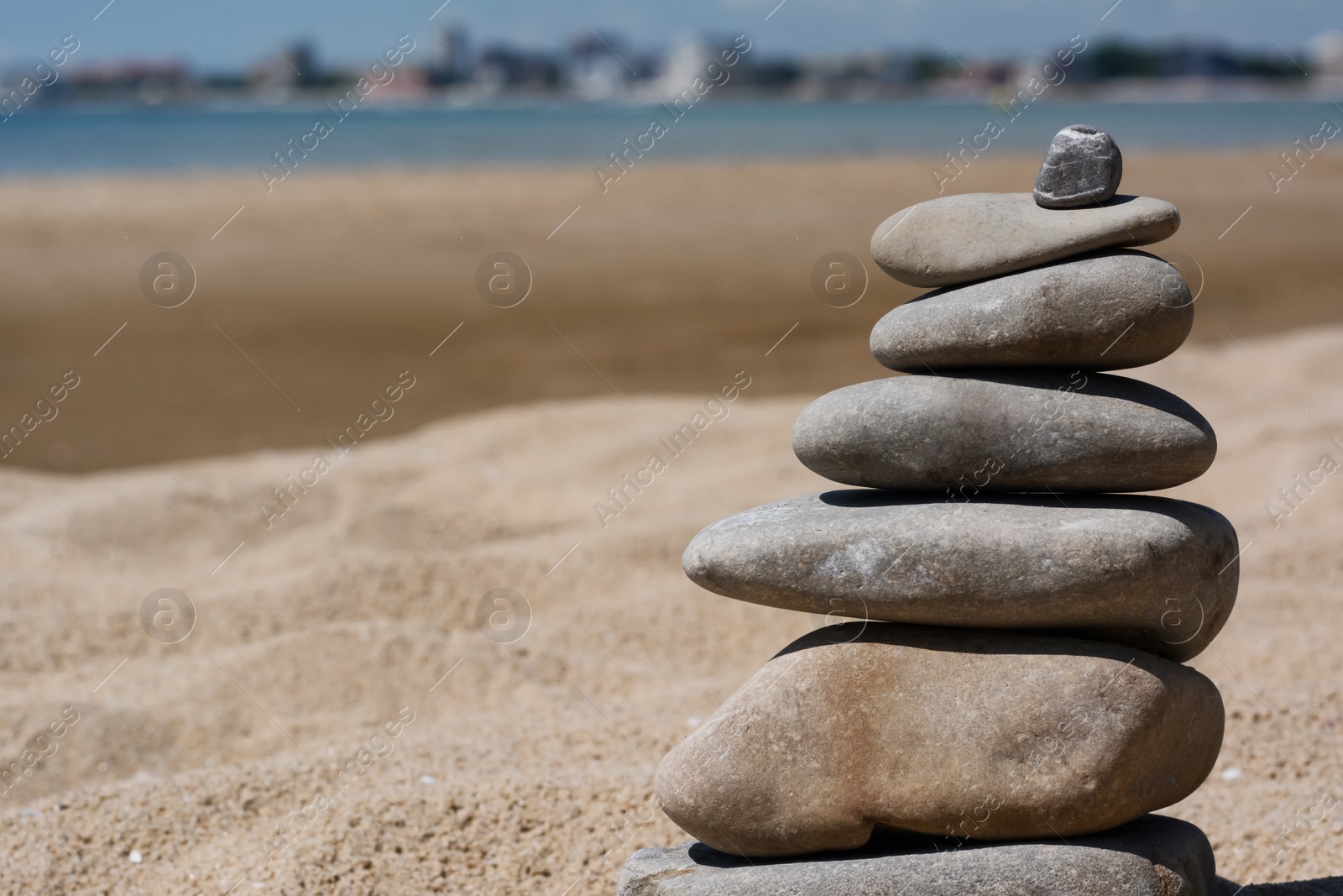 Photo of Stack of stones on beautiful sandy beach near sea, closeup. Space for text