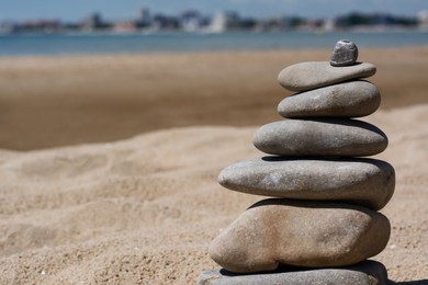 Photo of Stackstones on beautiful sandy beach near sea, closeup. Space for text