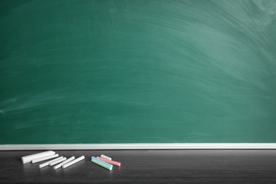 Chalk sticks on table near board in classroom