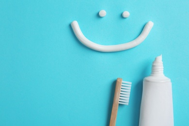 Photo of Smiling face made of toothpaste, tube, brush and space for text on color background, top view