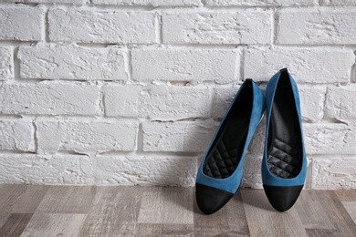 Pair of female shoes on floor against brick wall