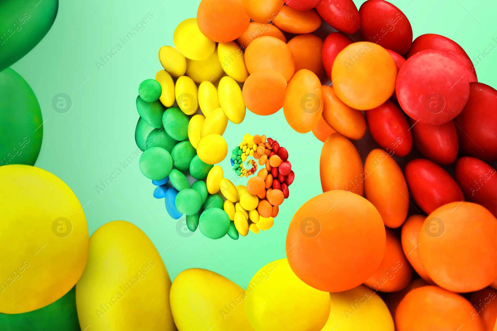Image of Whirl of colorful candies on mint color background