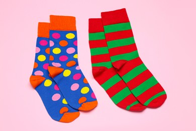 Different colorful socks on light pink background, flat lay