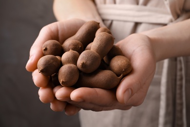 Photo of Woman holding fresh ripe tamarinds, closeup view