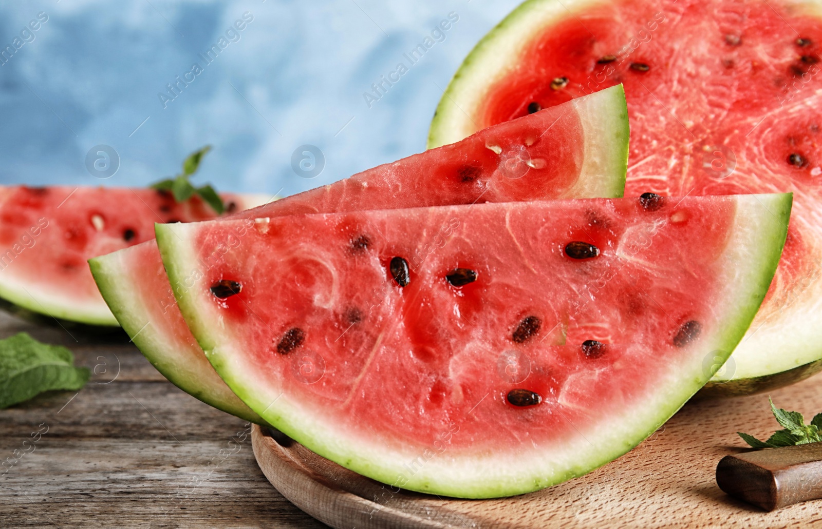 Photo of Wooden board with juicy watermelon slices on table