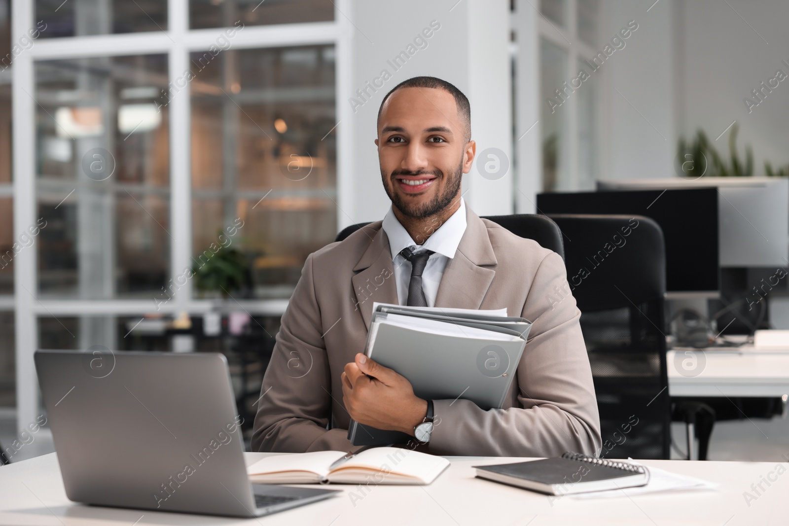 Photo of Happy man with folders working at table in office. Lawyer, businessman, accountant or manager