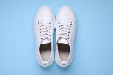 Photo of Pair of stylish white sneakers on light blue background, top view