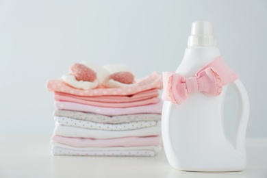 Photo of Detergent and children's clothes on white table