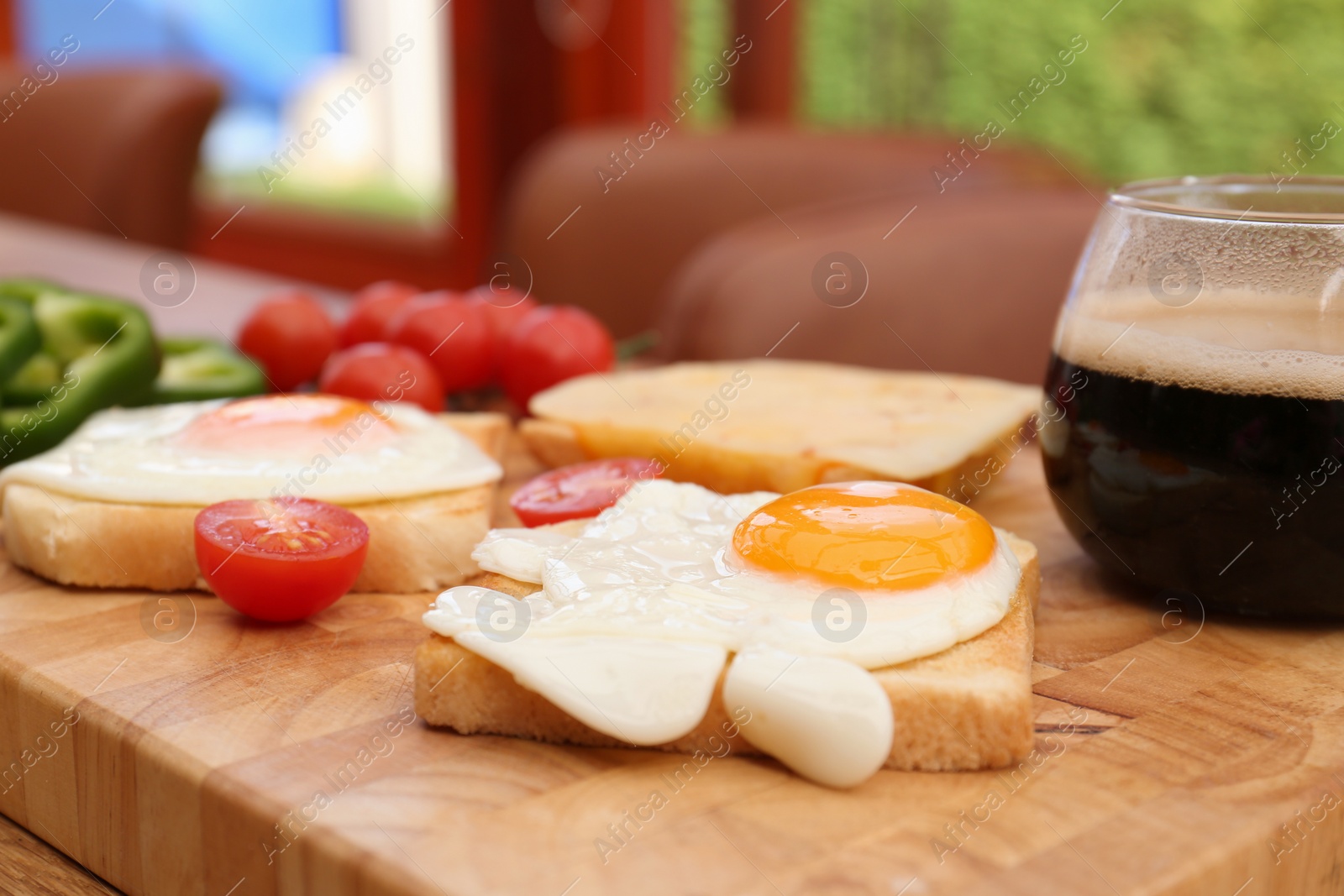 Photo of Tasty toasts with fried eggs and tomatoes on wooden table indoors, closeup