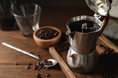 Photo of Brewed coffee in moka pot and beans on wooden table, closeup