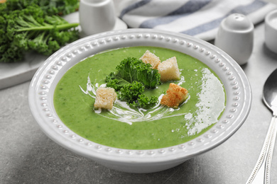 Photo of Tasty kale soup with croutons on grey table