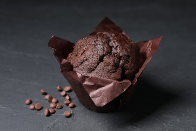 Photo of Tasty chocolate muffin on black textured table, closeup