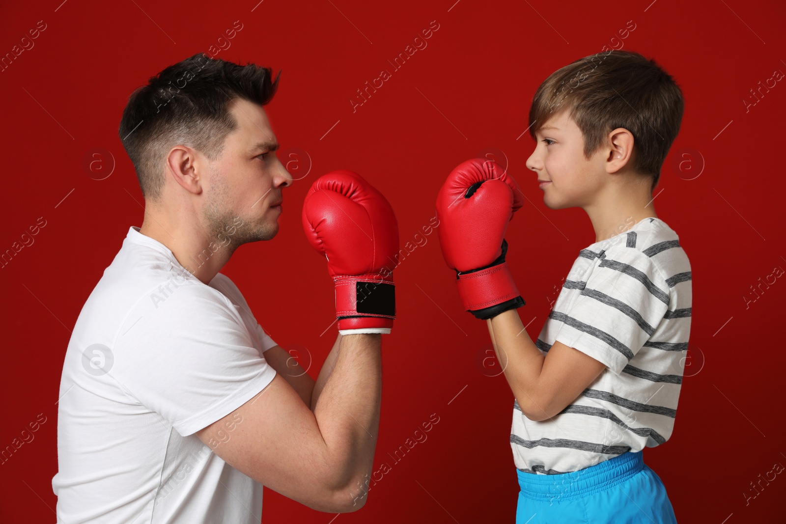 Photo of Dad and his son with boxing gloves on color background