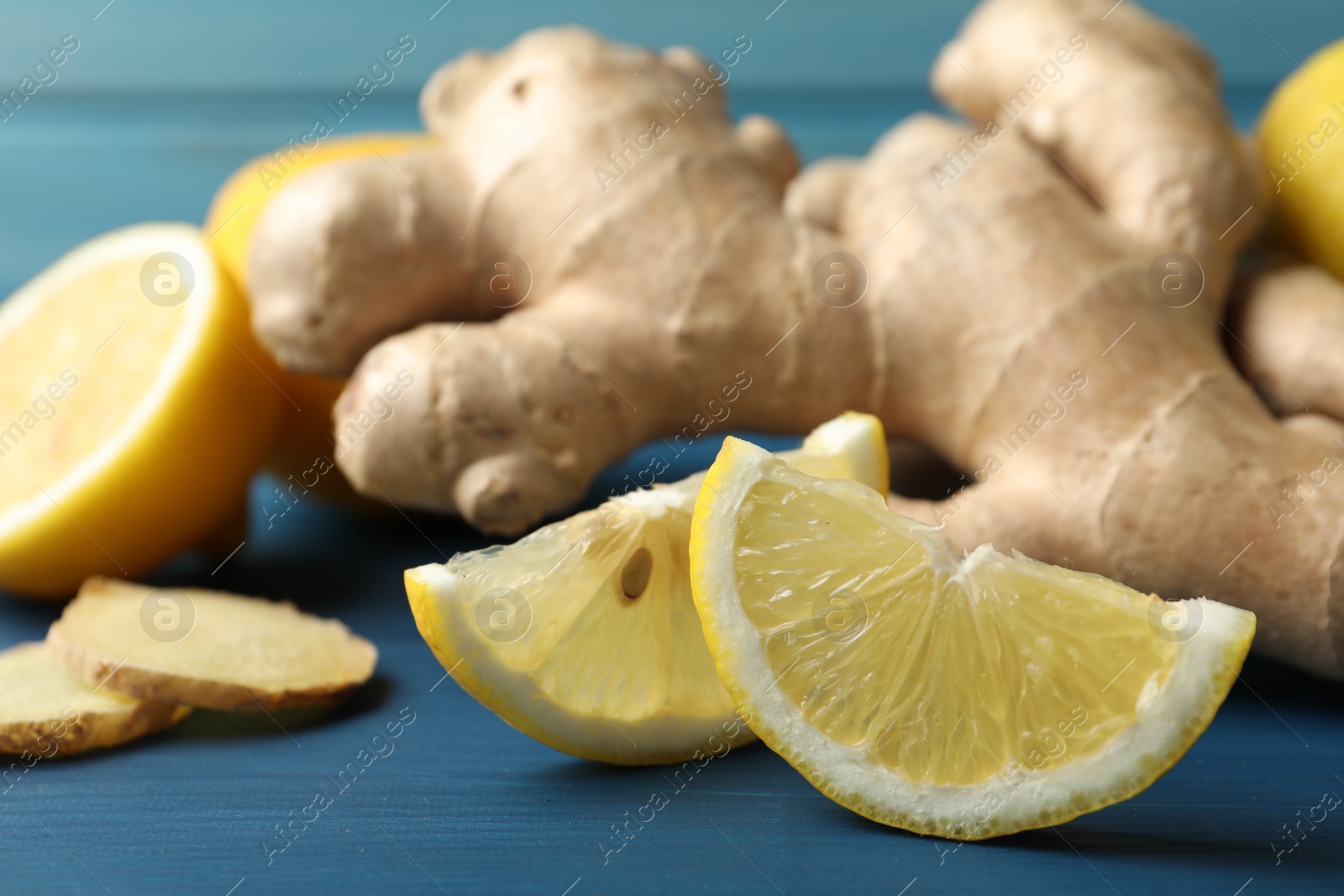 Photo of Fresh lemon and ginger on blue wooden table, closeup