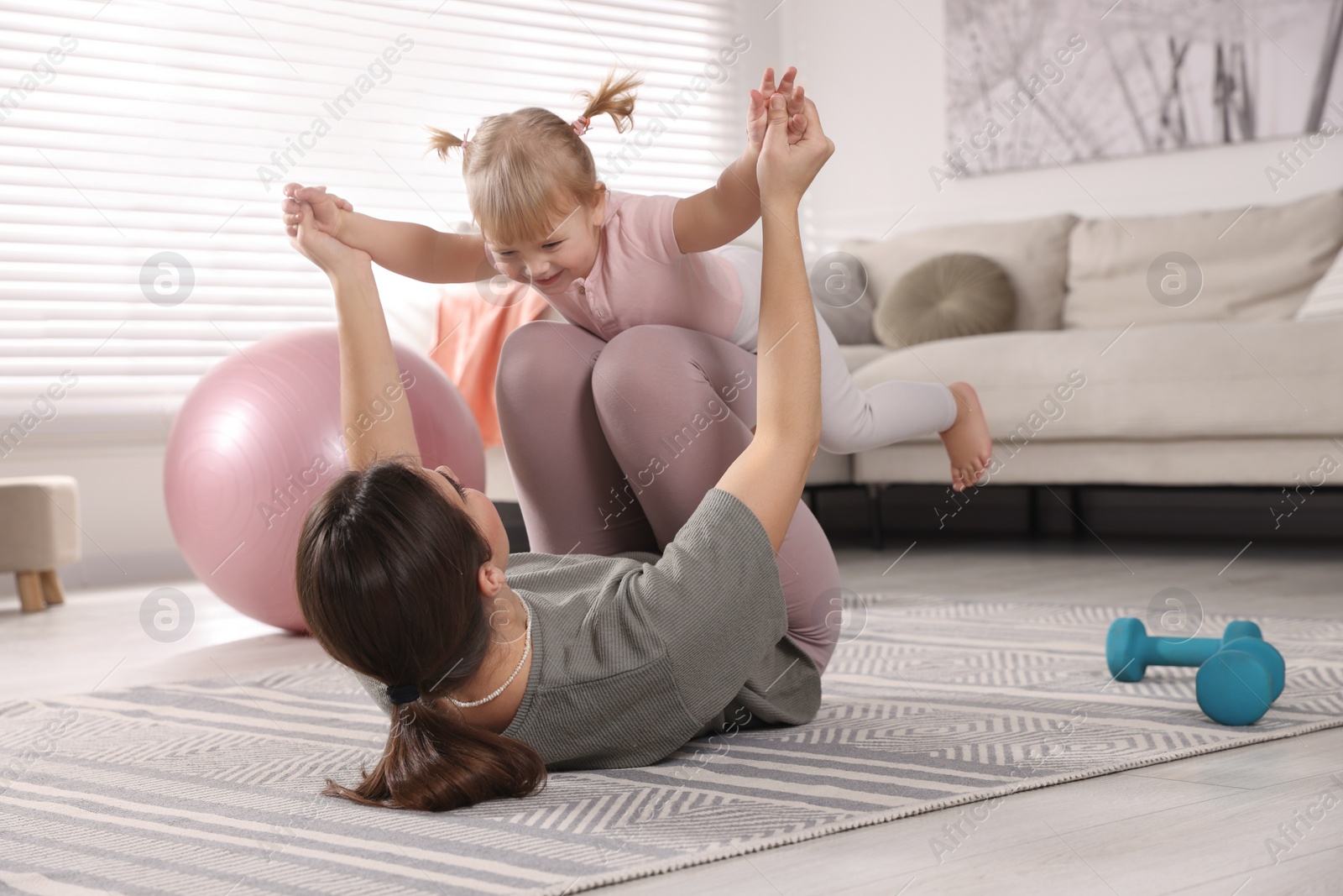 Photo of Mother doing exercise with her daughter at home