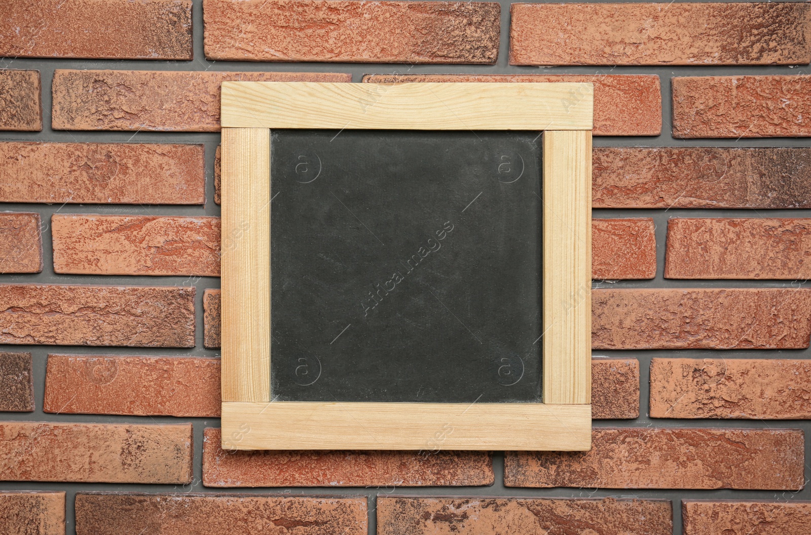 Photo of Small clean chalkboard hanging on brick wall