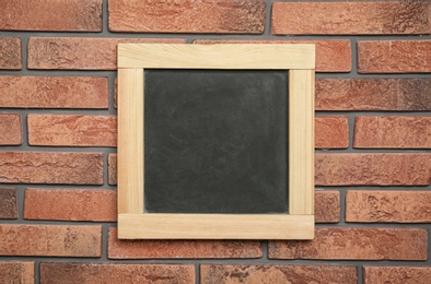 Photo of Small clean chalkboard hanging on brick wall