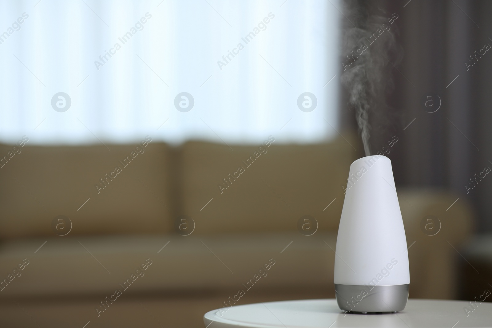 Photo of Aroma oil diffuser on table indoors. Space for text