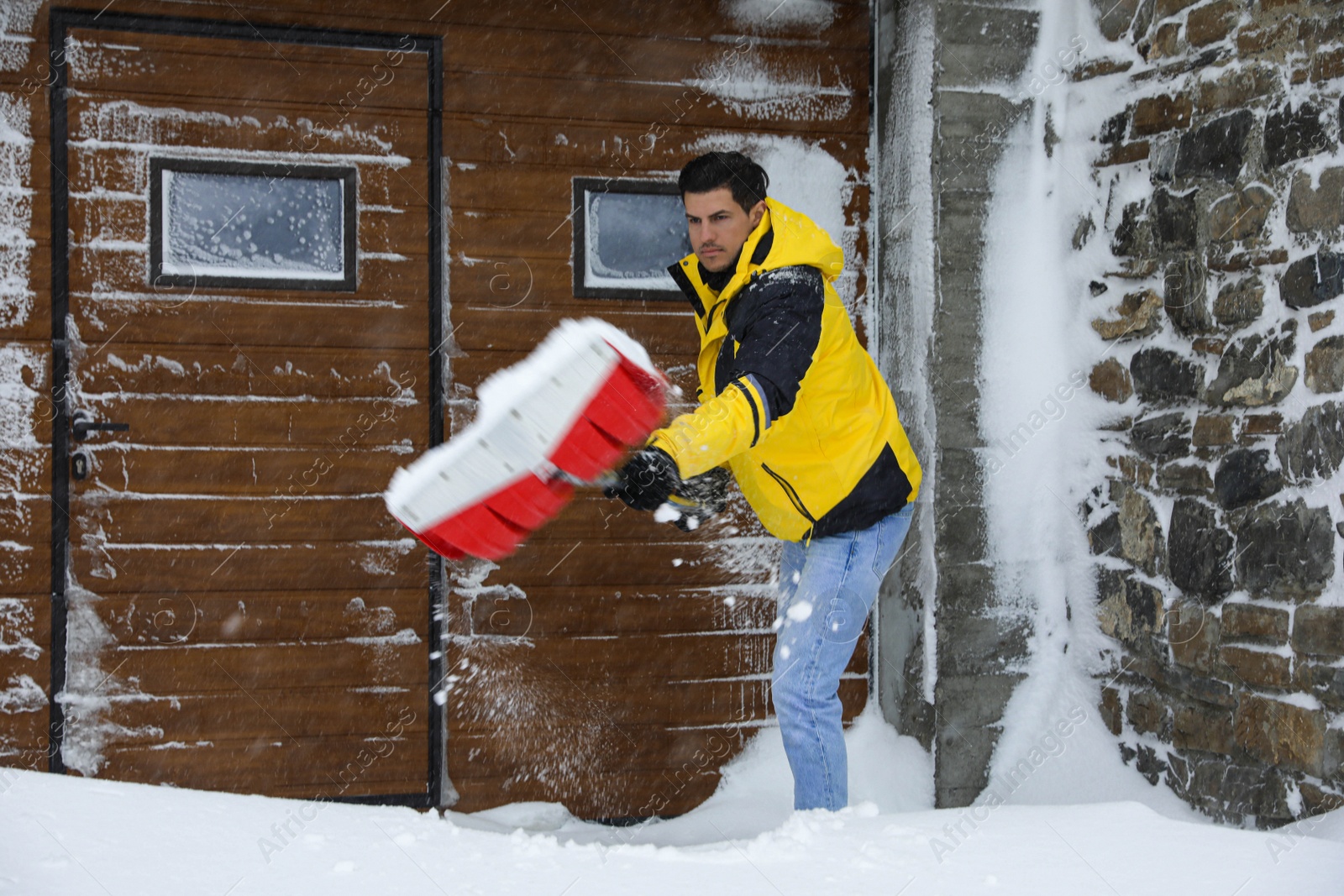 Photo of Man cleaning snow with shovel near his house