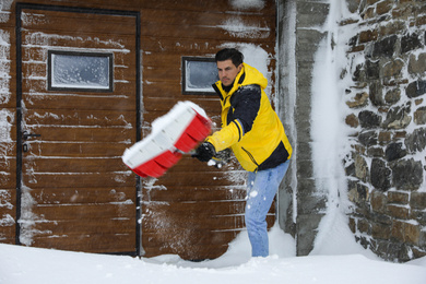 Man cleaning snow with shovel near his house