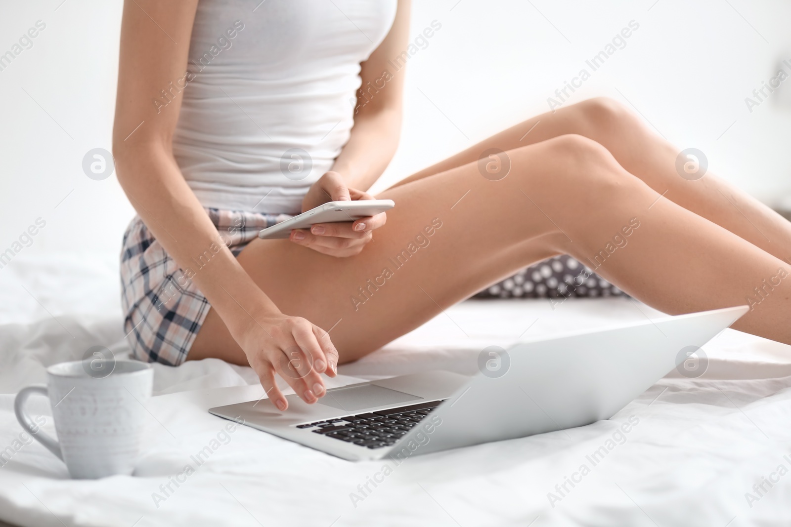 Photo of Female blogger with laptop and smartphone on bed