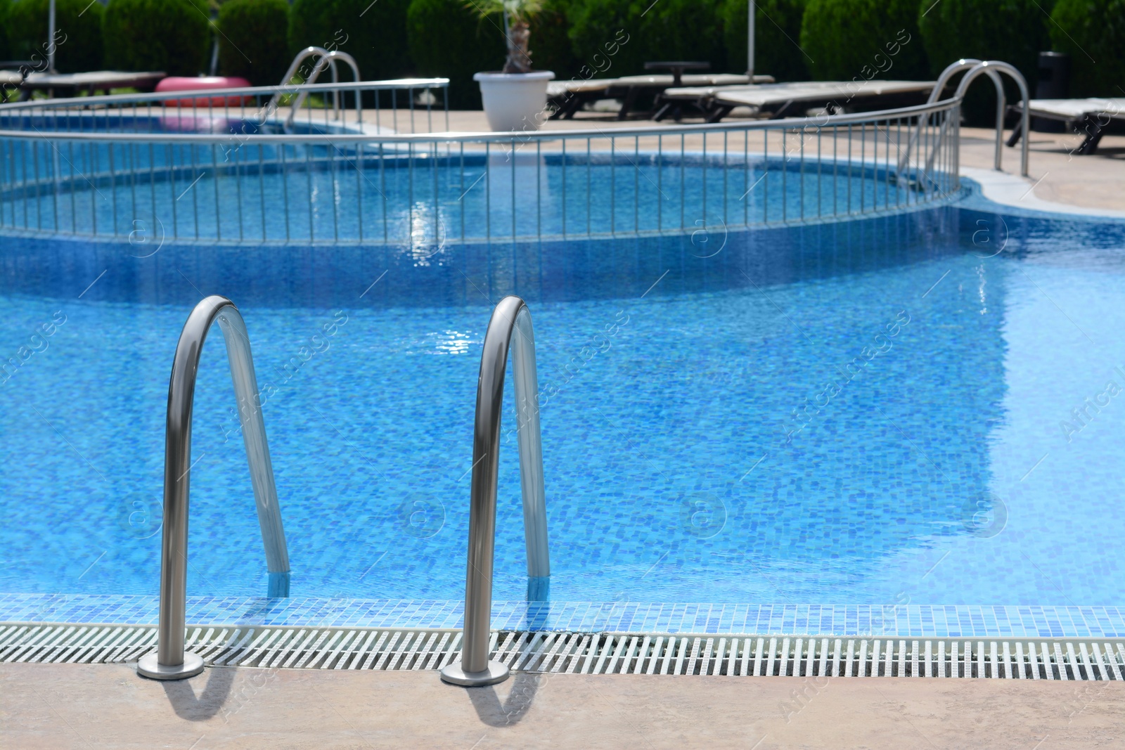 Photo of Outdoor swimming pool with ladder and handrails on sunny day, space for text