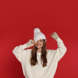 Photo of Beautiful young woman in white sweater and hat on red background. Winter season