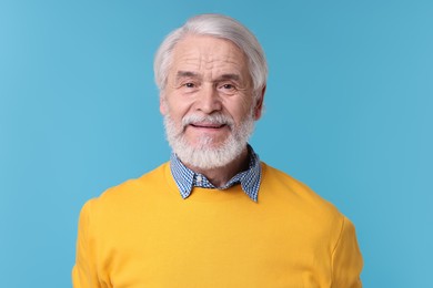 Portrait of stylish grandpa on light blue background