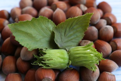 Pile of hazelnuts and leaves on table, closeup