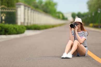 Photo of Photographer taking photo with professional camera on road. Space for text