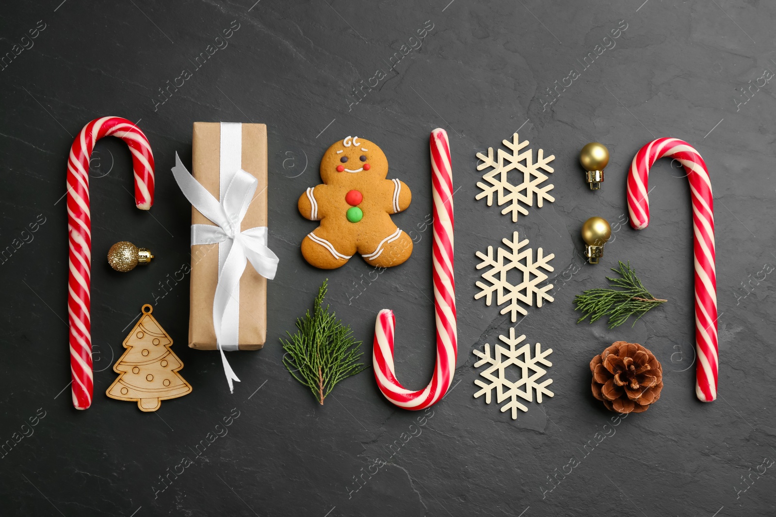 Photo of Flat lay composition with candy canes and Christmas decor on black table