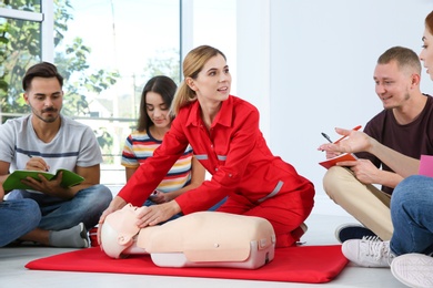 Photo of Instructor demonstrating CPR on mannequin at first aid class indoors