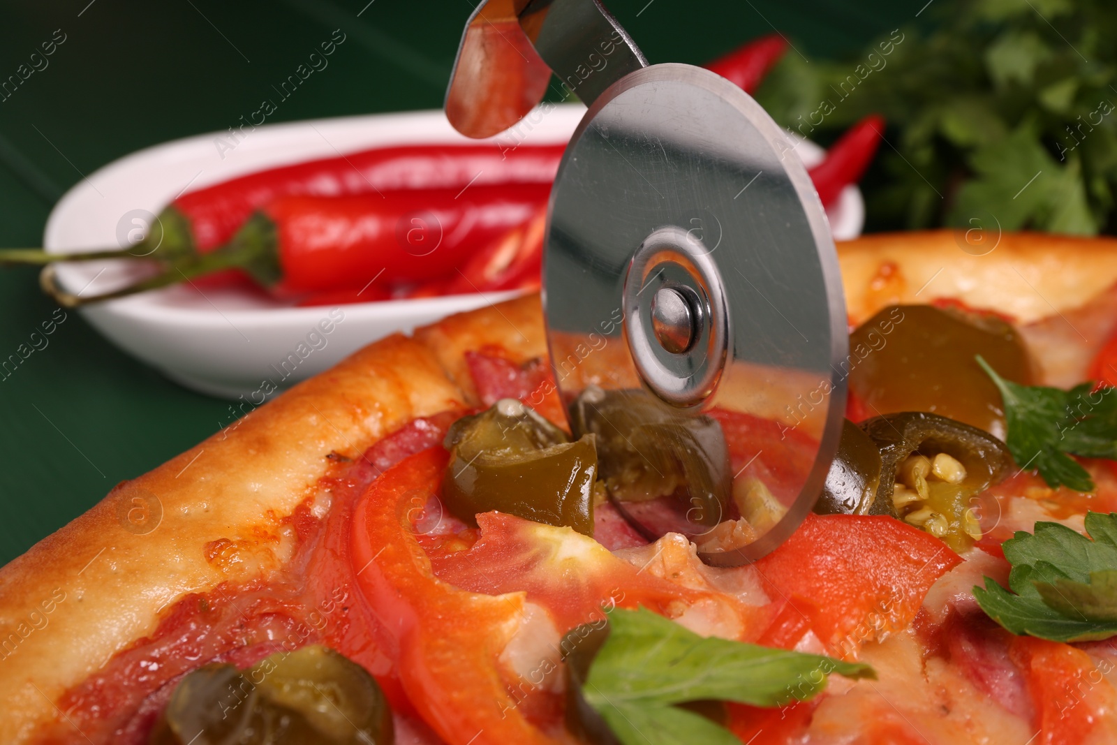 Photo of Cutting delicious pizza Diablo at table, closeup