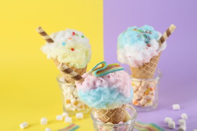 Photo of Sweet cotton candies in waffle cones and marshmallows on color background, closeup